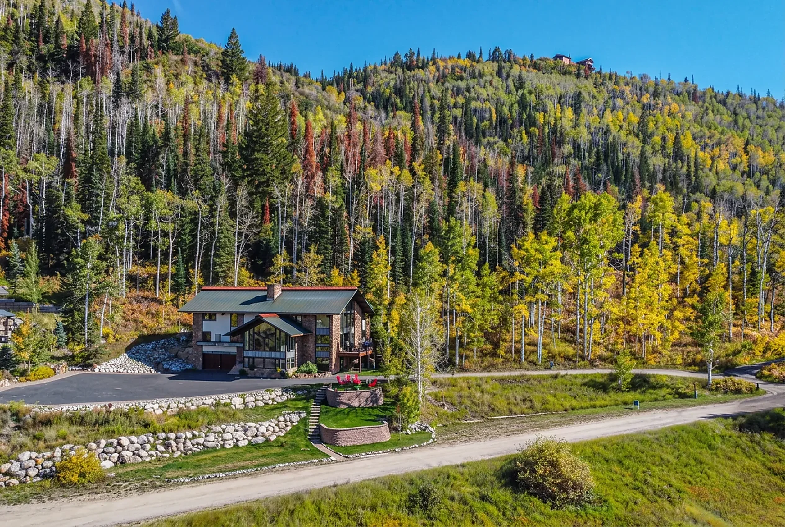 Mountain vacation home with a metal roof set below a hillside of golden autumn aspens